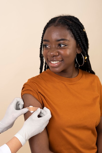 Foto gratuita mujer sonriente recibiendo una pegatina en el brazo después de la vacuna.