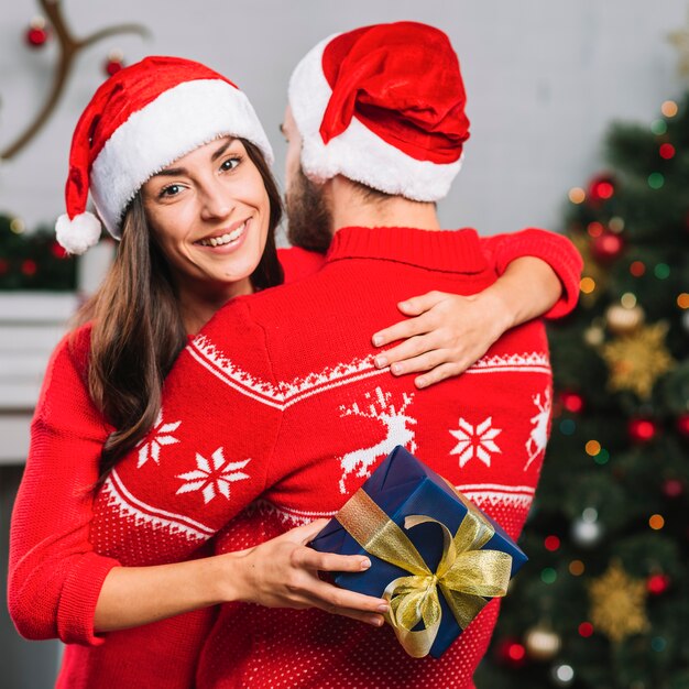 Mujer sonriente con el regalo que abraza al hombre