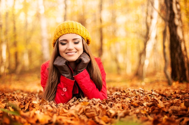 Mujer sonriente relajándose en el parque en otoño