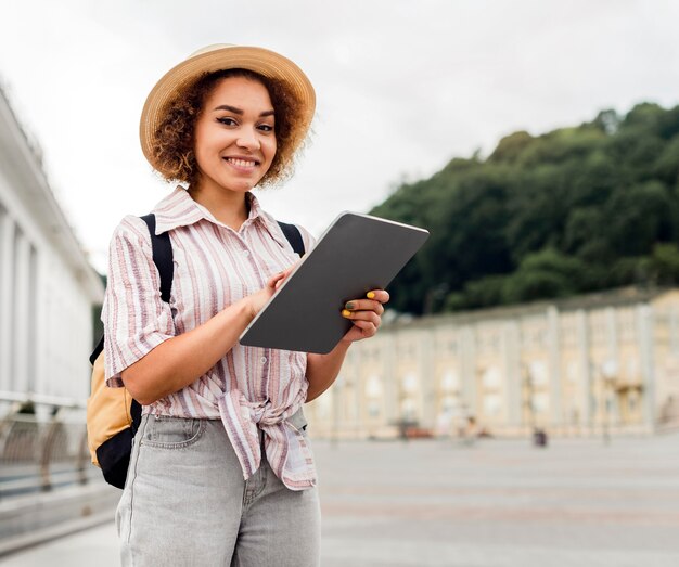 Mujer sonriente revisando su tableta para direcciones