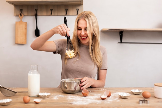 Mujer sonriente revuelva los huevos en el tazón