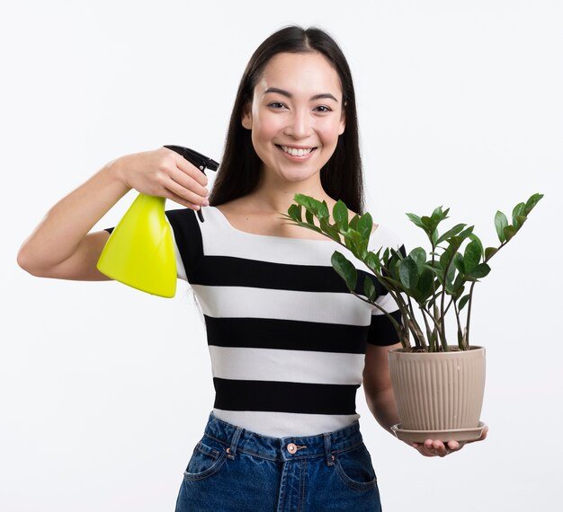 Mujer sonriente rociando hojas de flores