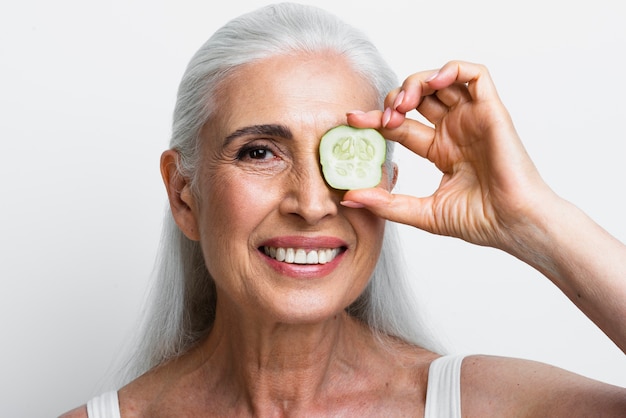 Mujer sonriente con una rodaja de pepino