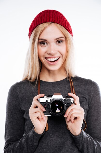 Mujer sonriente en ropa casual de pie y sosteniendo la cámara retro