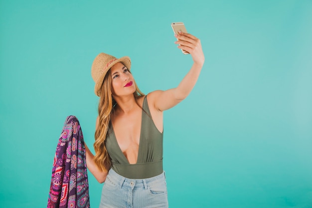 Mujer sonriente en ropa de playa haciendo un selfie