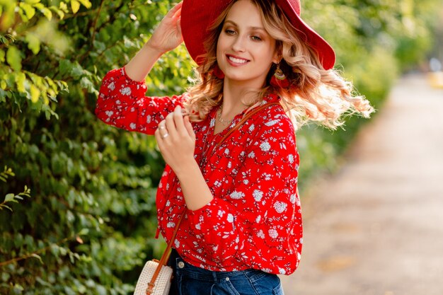 Mujer sonriente rubia con estilo muy atractiva en traje de moda de verano de sombrero rojo de paja y blusa