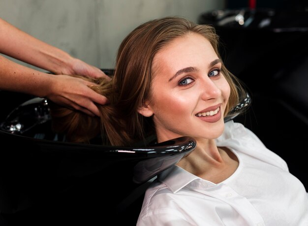 Mujer sonriente rubia que se lava el cabello