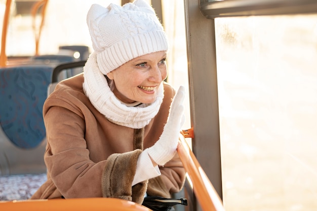 Mujer sonriente saludando desde el autobús