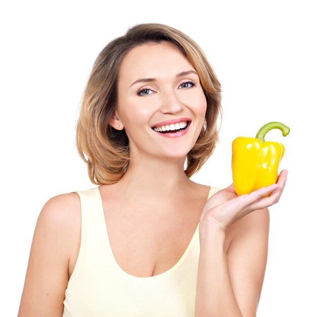 La mujer sonriente sana joven sostiene la pimienta - aislada en blanco.