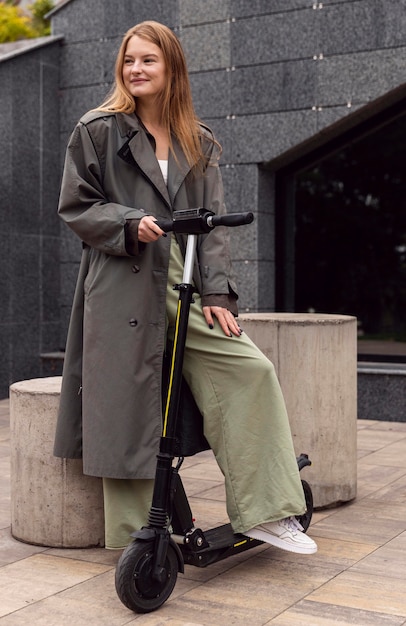 Mujer sonriente con scooter eléctrico en la ciudad