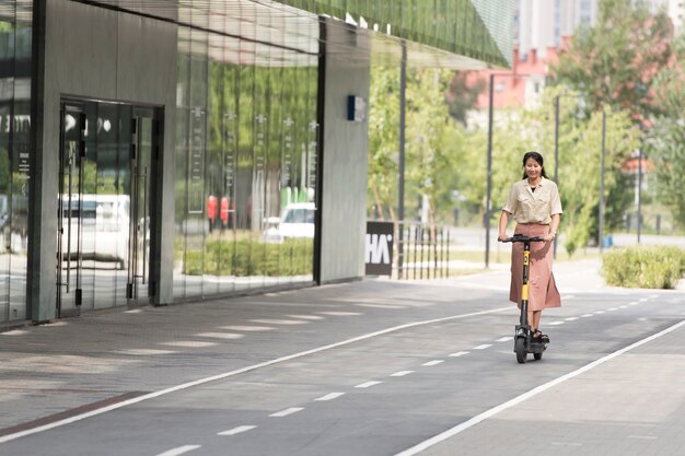 Mujer sonriente con scooter full shot