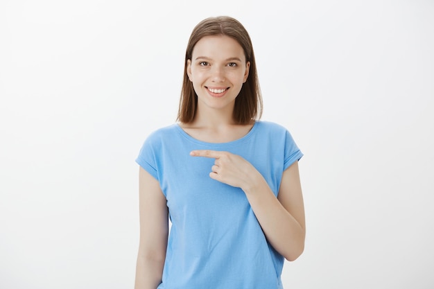 Mujer sonriente segura y asertiva que invita al evento de salida, señalando con el dedo a la izquierda