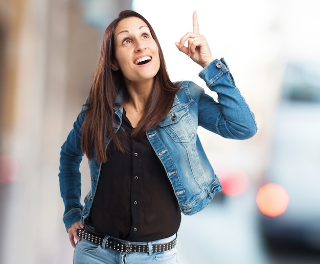 Mujer sonriente señalando hacia arriba