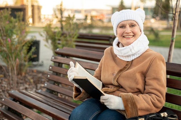 Mujer sonriente sentada en un banco y leyendo