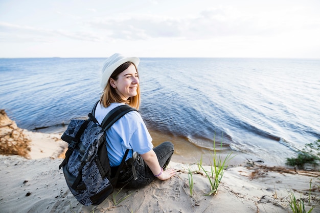 Mujer sonriente sentada cerca del mar