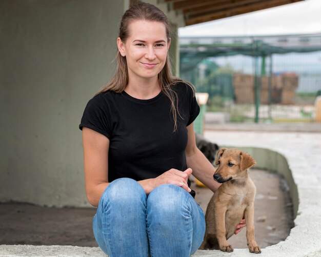 Mujer sonriente sentada junto al perro de rescate en el refugio