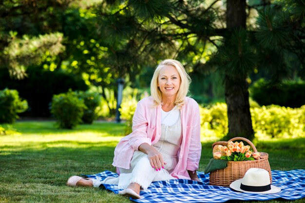 Mujer sonriente sentada junto a una cesta de picnic