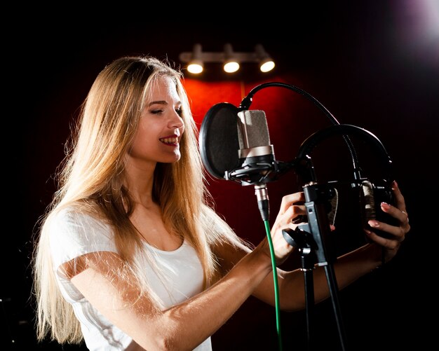 Mujer sonriente sentada de lado y con auriculares