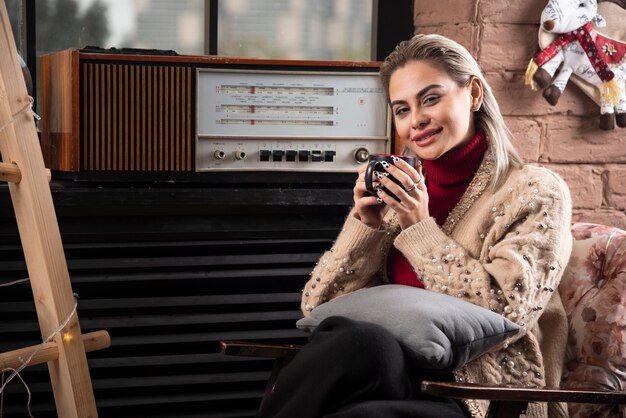 Una mujer sonriente sentada con un libro y tomando café