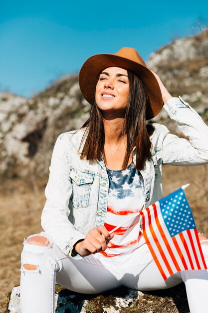 Mujer sonriente sentada en piedra con bandera