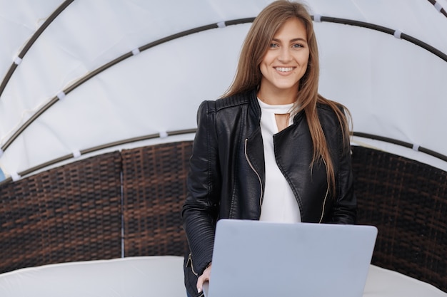 Mujer sonriente sentada en un sillón de mimbre