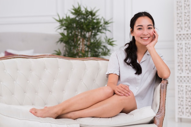 Foto gratuita mujer sonriente sentada en el sofá