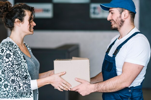 Mujer sonriente y servicio de mensajería con paquete