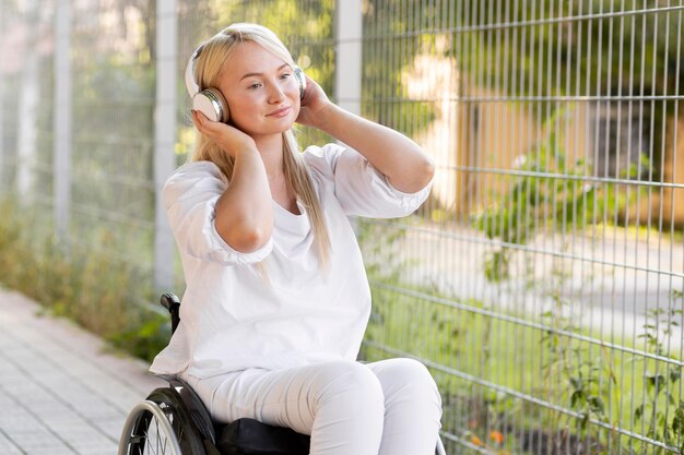 Mujer sonriente en silla de ruedas con auriculares