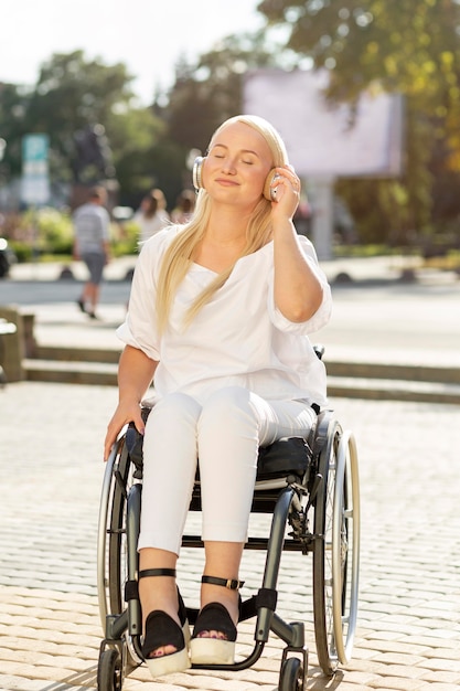 Mujer sonriente en silla de ruedas escuchando música con auriculares fuera