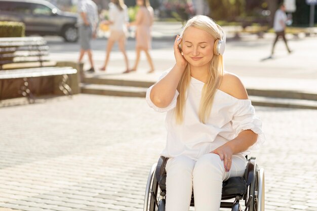 Mujer sonriente en silla de ruedas escuchando música con auriculares