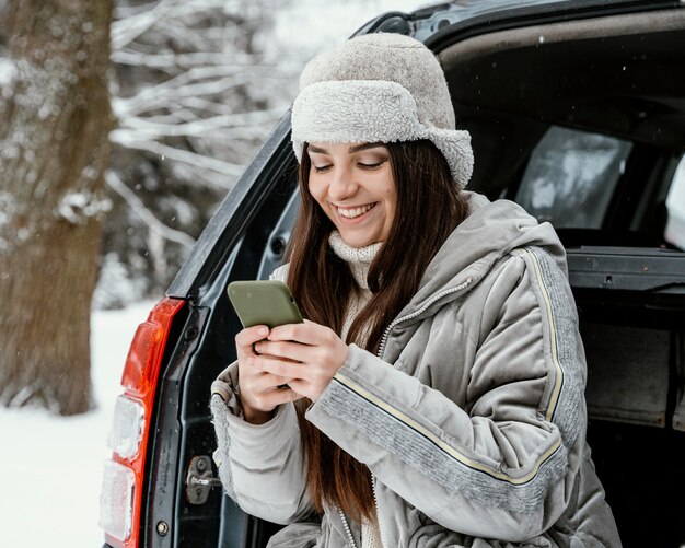 Mujer sonriente con smartphone durante un viaje por carretera