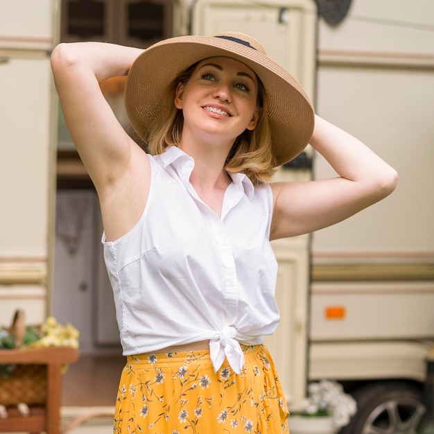 Mujer sonriente con sombrero disfrutando de un viaje con una caravana