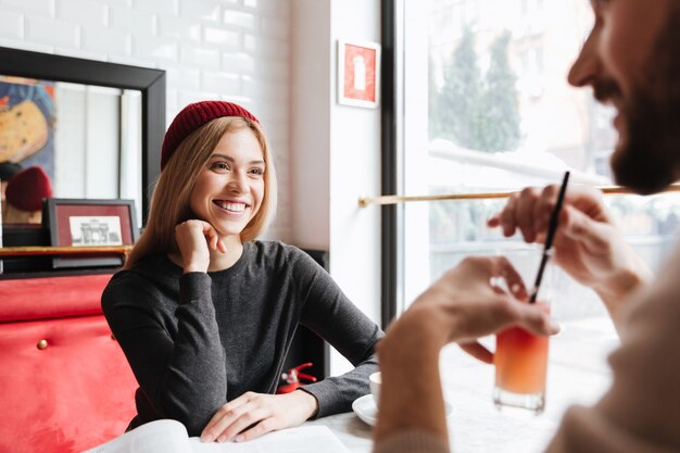 Mujer sonriente en sombrero rojo hablando con hombre