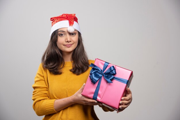 Mujer sonriente con sombrero rojo de Santa Claus con regalo de Navidad.