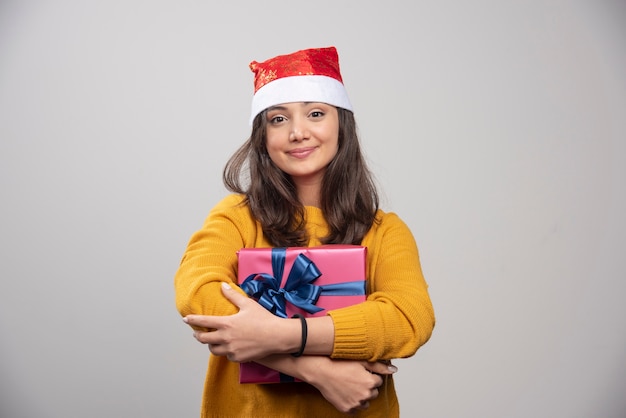 Foto gratuita mujer sonriente con sombrero rojo de santa claus con regalo de navidad.