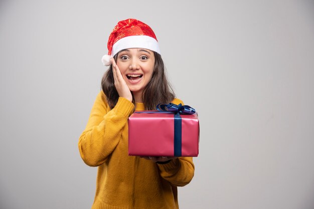 Mujer sonriente con sombrero de Santa con caja de regalo.