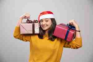 Foto gratuita mujer sonriente con sombrero de santa mostrando cajas de regalo.