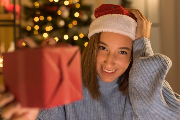 Mujer sonriente con sombrero de santa con regalo de navidad