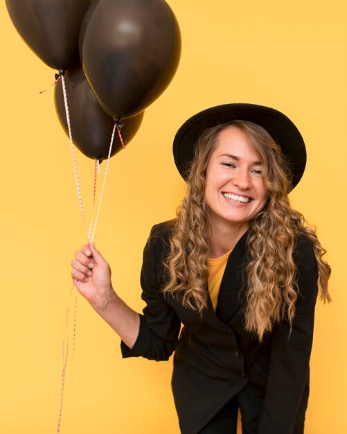 Mujer sonriente con sombrero y sosteniendo globos