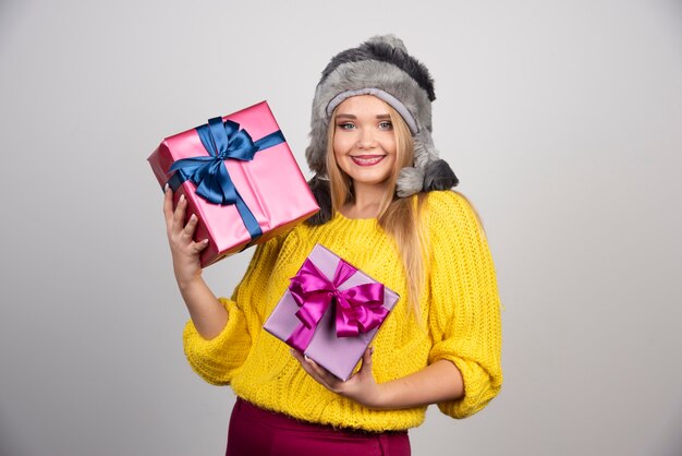 Una mujer sonriente con sombrero sosteniendo regalos de Navidad.