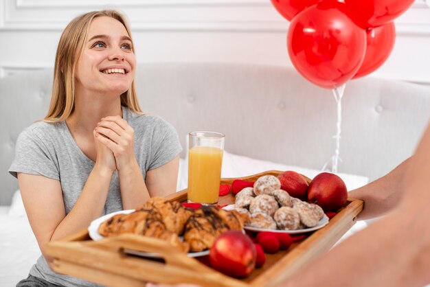 Mujer sonriente sorprendida con desayuno en la cama