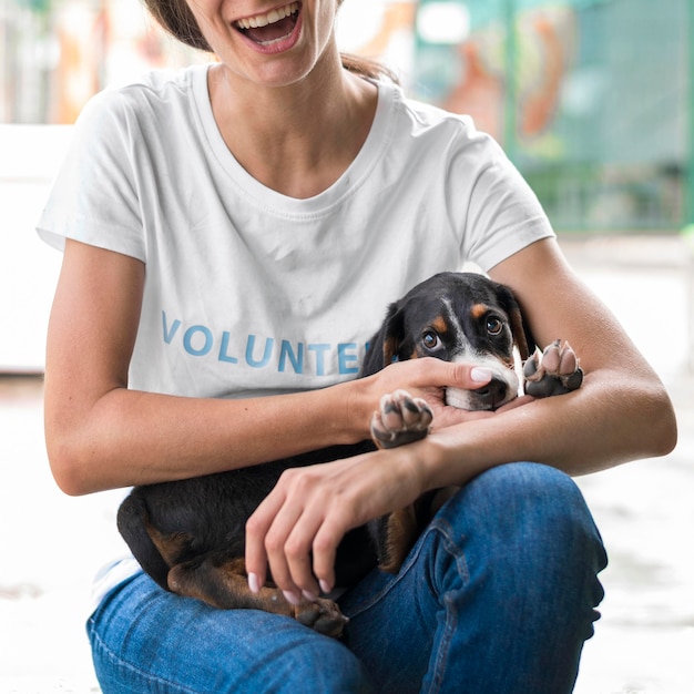 Mujer sonriente sosteniendo adorable perro de rescate en el refugio