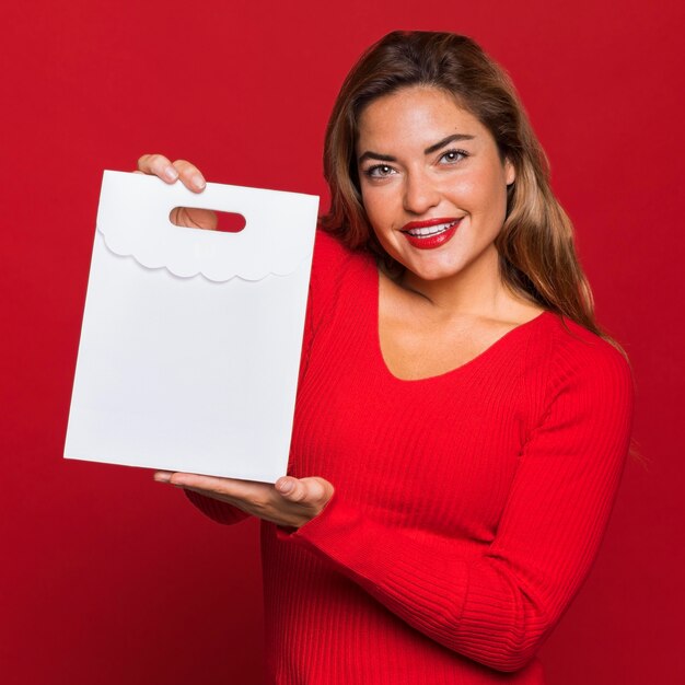 Mujer sonriente sosteniendo una bolsa de papel