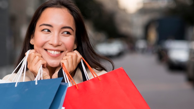 Mujer sonriente sosteniendo bolsas de la compra después de la venta de compras