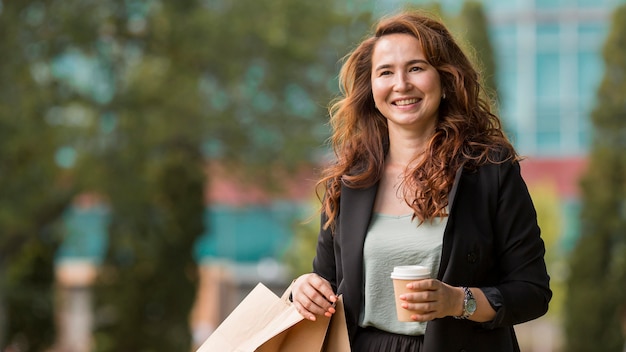 Foto gratuita mujer sonriente sosteniendo bolsas de la compra y una taza de café