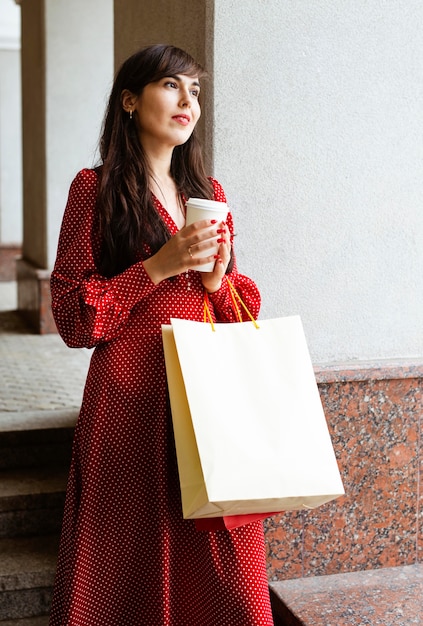 Foto gratuita mujer sonriente sosteniendo bolsas de compras y café