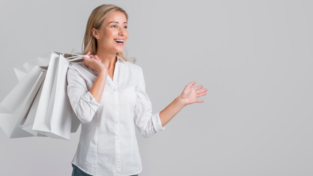 Mujer sonriente sosteniendo bolsas de compras y feliz por la juerga de compras que hizo