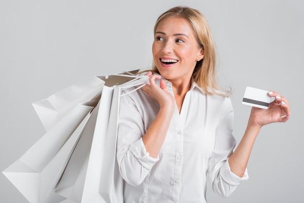 Mujer sonriente sosteniendo bolsas de compras y tarjeta de crédito
