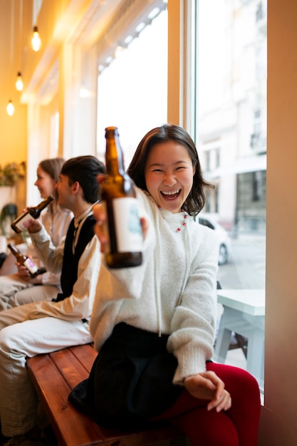 Mujer sonriente sosteniendo una botella de kombucha vista frontal