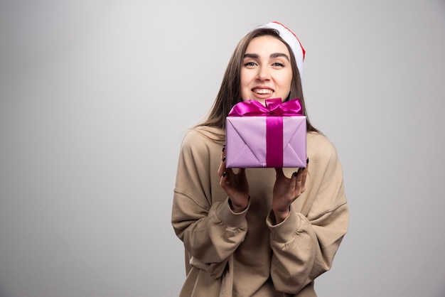 Mujer sonriente sosteniendo una caja de regalo de Navidad.